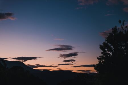 sunset sky over the hills and mountains in Tasmania, Australia with deep tones and trees silhouettes