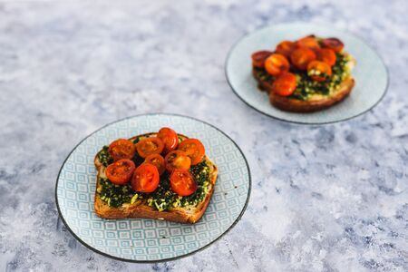 healthy plant-based food recipes concept, homemade bruschetta with celeri leaves pesto vegan cheese and cherry tomato on breadの写真素材