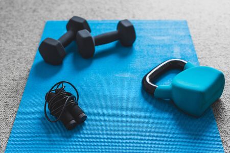 home gym concept, room with dumbbells kettlebell foam roller and push-up handles on yoga mat to...