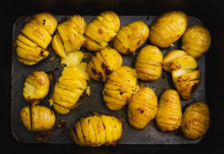 healthy wholesome food ingredients concept, oven roasted baked potatoes on tray with slicesの写真素材