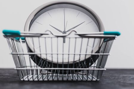 concept of flash sales and time limited marketing offers, big clock inside grocery shopping basketの写真素材