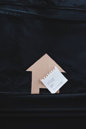 isolation and travel restrictions to flatten the curve against the covid-19 virus outbreak, open empty suitcase with nothing packed inside except for Stay Home message and house icon next to itの写真素材
