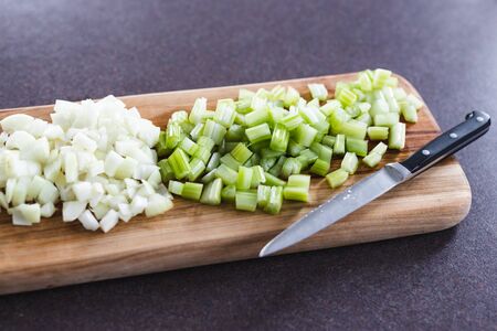 healthy plant-based food ingredients, chopped onions and celeri on cutting board with knife