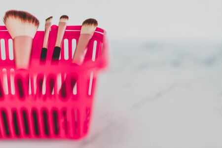beauty industry and essential products concept, pink shopping basket with variety of make-up brushes in it for face and eye make-upの写真素材
