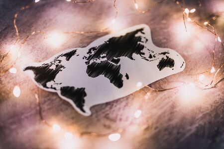 world map surrounded by fairy lights on concrete desk shot at shallow depth of fieldの写真素材