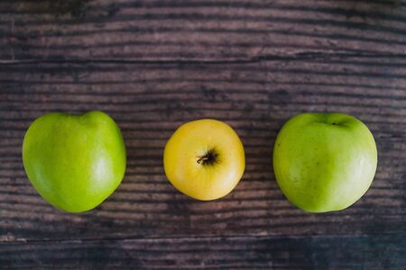 healthy plant-based food ingredients concept, group of  green apples lined up with a unique yellow...