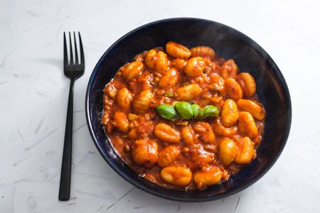 healthy plant-based food recipes concept, potato gnocchi with red pesto sauce and basil on topの写真素材