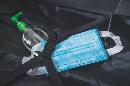 travel industry and flying during covid-19, carry-on luggage with surgical face mask and hand...