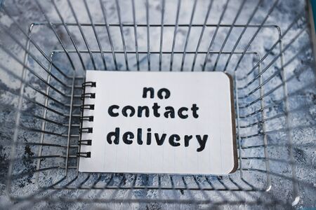 the new normal after covid-19, No Contact Delivery text on notepad inside shopping basket symbol of purchases during isolation and lockdownの写真素材
