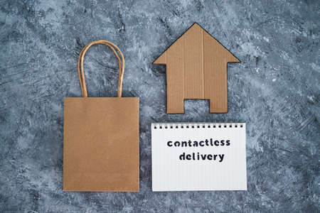 the new normal after covid-19, Contactless Delivery text on notepad with shopping bag and house icon concept of purchases during isolation and lockdownの写真素材