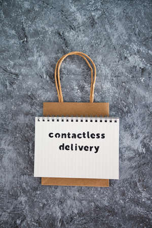 the new normal after covid-19, Contactless Delivery text on notepad with shopping bag concept of purchases during isolation and lockdownの写真素材