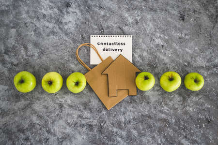 the new normal after covid-19, Contactless Delivery text on notepad among apples and with shopping...