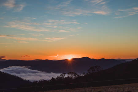 sunrise sky with beautiful clouds rolling over the hills of Tasmania, Australiaの写真素材