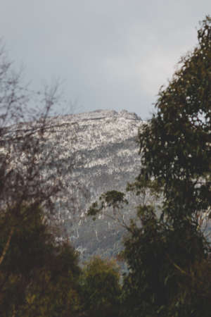 snowy Tasmanian mountain landscape with vegetation in the foreground shot with telephoto lens