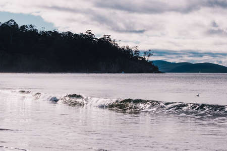 HOBART, AUSTRALIA - July 5th, 2020: view of Kingston Beach on a cloudy winter day with people on...