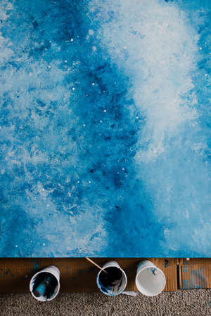 arts and craft hobbies concept, blue and white acrylic painting with colors in plastic cups and...