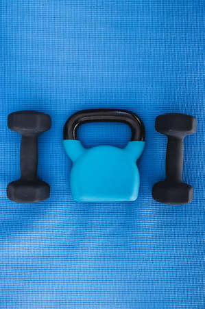 healthy and fit lifestyle concept, home gym equipment on yoga mat including dumbbells and kettlebell