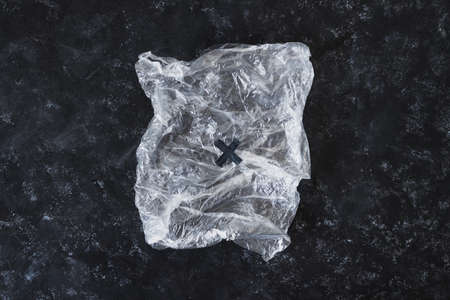 ecological choices and environmental awareness concept, scrunched plastic bag crossed out on dark backgroundの写真素材