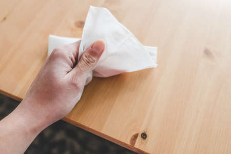 disinfecting surfaces from bacteria or viruses sill-life, hand cleaning woooden coffee table with disinfectant wet wipe concept of the new normal after covid-19の写真素材