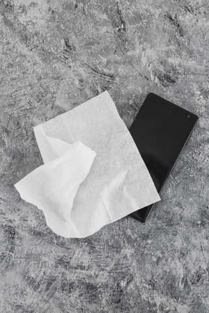 the new normal after covid-19 and concet of sanitizing surfaces, cleaning smartphone with disinfectant wipe to flatten the curve and prevent viruses and bacteriaの写真素材