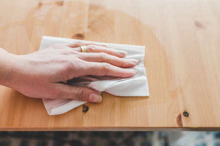 disinfecting surfaces from bacteria or viruses sill-life, hand cleaning woooden coffee table with disinfectant wet wipe concept of the new normal after covid-19の写真素材
