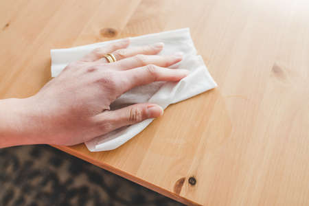 disinfecting surfaces from bacteria or viruses sill-life, hand cleaning woooden coffee table with disinfectant wet wipe concept of the new normal after covid-19の写真素材