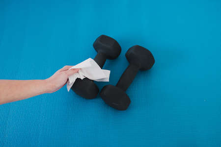 the new normal for businesses after covid-19, hand cleaning gym equipment with disinfectant wipe against virus and bacteriaの写真素材