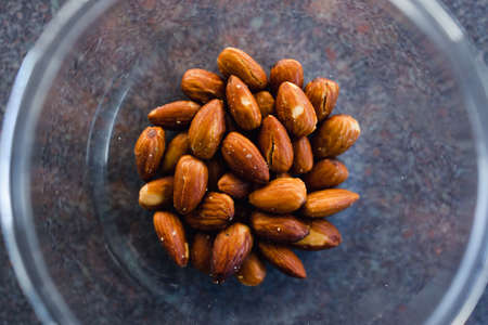 simple food ingredients concept, salted roasted almonds in clear bowl
