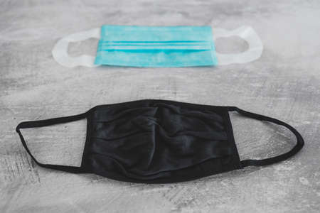 the new normal after the covid-19 virus outbreak, different face masks including surgical mask, fabric and construction ones on concrete surfaceの写真素材