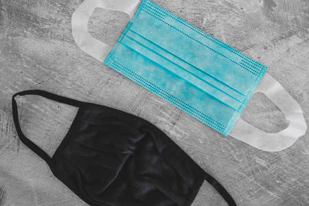 the new normal after the covid-19 virus outbreak, different face masks including surgical mask, fabric and construction ones on concrete surfaceの写真素材