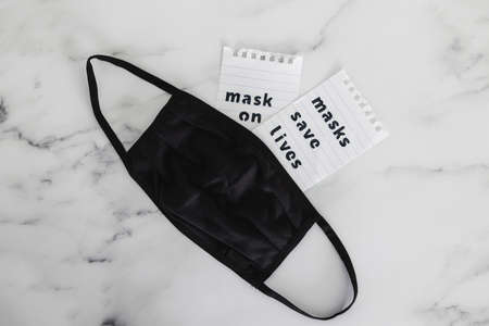 protection against the covid-19 virus outbreak and flattening the curve, reusable fabric face mask with text Masks save lives next to itの写真素材