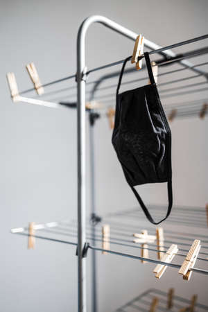 the new normal after the covid-19 virus outbreak and pandemic, reusable fabric face mask just washed and hung to dry on clothes airerの写真素材
