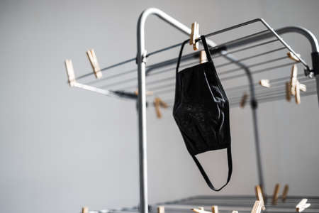 the new normal after the covid-19 virus outbreak and pandemic, reusable fabric face mask just washed and hung to dry on clothes airerの写真素材