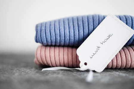 shopping and marketing concept, knit jumpers in alternative colours with Must Have text on price tag