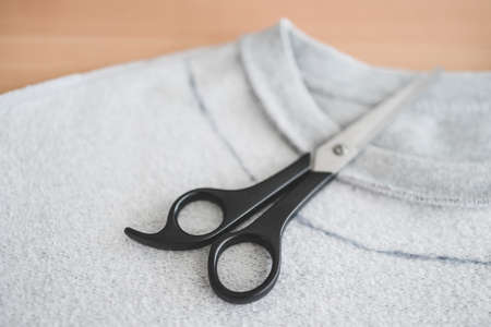 fashion diy and upcycling old clothes concept, sweatshirt with scissors to cut a new neckline