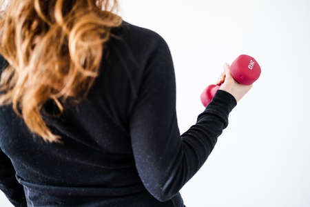 home fitness and online coaching concept, woman in sporty clothes holding dumbbell and exercising...