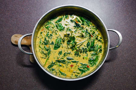 healthy plant-based food recipes concept, vegan green curry with spinach broccolini kale and stir...
