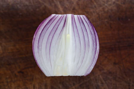 simple food ingredients concept, close up of half of red onion on wooden cutting board