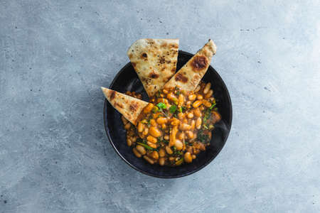 healthy plant-based food recipes concept, vegan butter beans cannellini and cauliflower stew in pumpkin sauce with garlic naan breadの写真素材