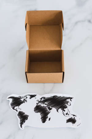 concept of global trade and worldwide deliveries, miniature postal parcel next to world mapの写真素材