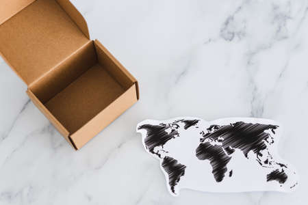 concept of global trade and worldwide deliveries, miniature postal parcel next to world mapの写真素材