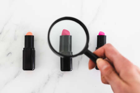 analyzing make-up ingredients concept, set of lipsticks with magnifying glassの写真素材