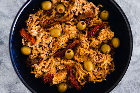 healthy plant-based food recipes concept, vegan breadcrumbed ginger noodles with sundried tomatoes and olivesの写真素材