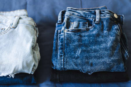 tidying up and organizing your wardrobe, different jeans in various denim colors getting sorted out in pilesの写真素材