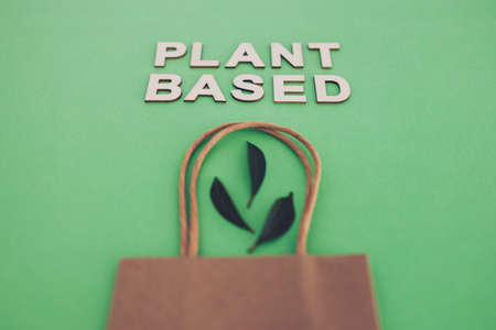 sustainable consumer choices for the environment, plant-based text with shopping bag and leaves on...