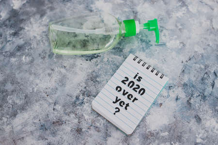 life after the covid-19 virus pandemic conceptual image, memo with text Is 2020 over yet next to hand sanitizer bottleの写真素材