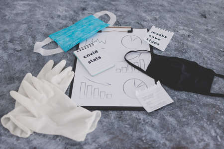 life after the covid-19 virus pandemic conceptual image, clipboard with graph and Covid Stats text surrounded by masks disposable gloves and memos about staying home and wearing a maskの写真素材