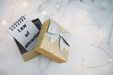 law of attraction conceptual image, text on notepad inside of present box surrounded by fairy lightsの写真素材