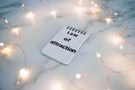 law of attraction conceptual image, text on notepad surrounded by fairy lightsの写真素材