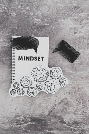 positivity and law of attraction conceptual image, notepad with Mindset text with different thought bubbles and gearwheel mechanism next to itの写真素材
